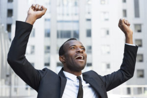 Business winner. Happy young African man in formalwear keeping arms raised and expressing positivity while standing outdoors